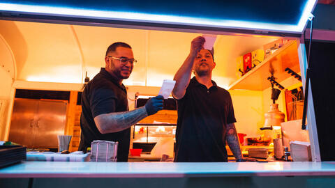 Two people working together in the kitchen of a restaurant.