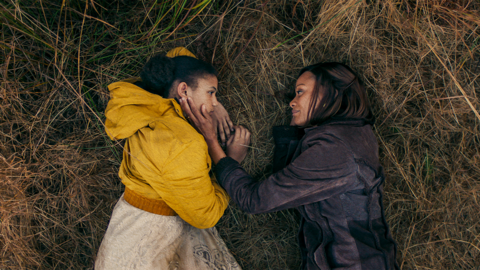 A child and her foster parent lay beside one another in a field