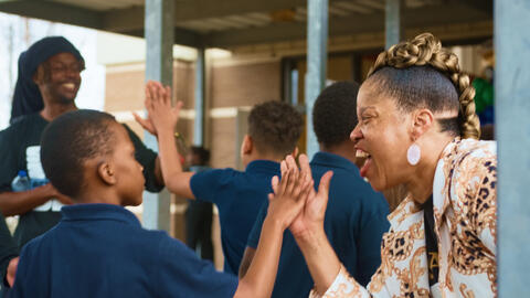 Student giving a high five to adults. 