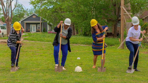 Group of people on a farm with digging shovels.