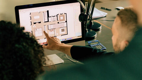 Person pointing at a laptop screen.