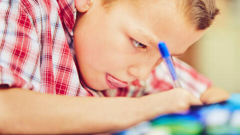 Student writing with a pen.