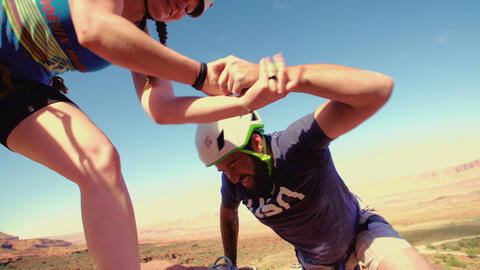 Person helping another climb up a mountain.