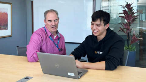 Employer and teenager on laptop.
