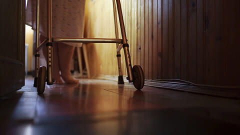 An elderly woman walking at home with a walker.