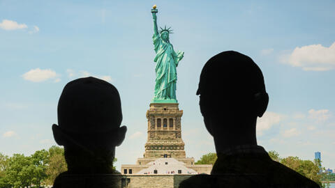 Two people looking at the Statue of Liberty.