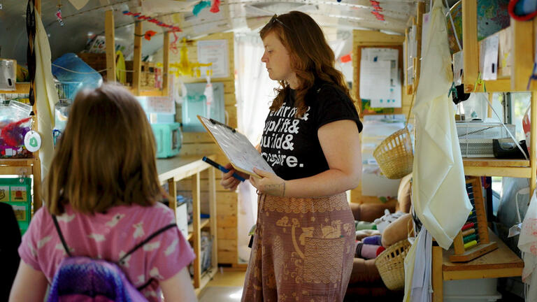 Teacher with student in classroom on a bus.