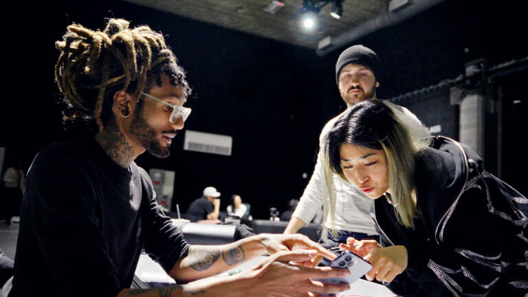 A group of workers looking at a phone.