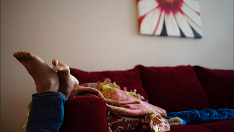 a child's feet on the legs of a couch from the floor