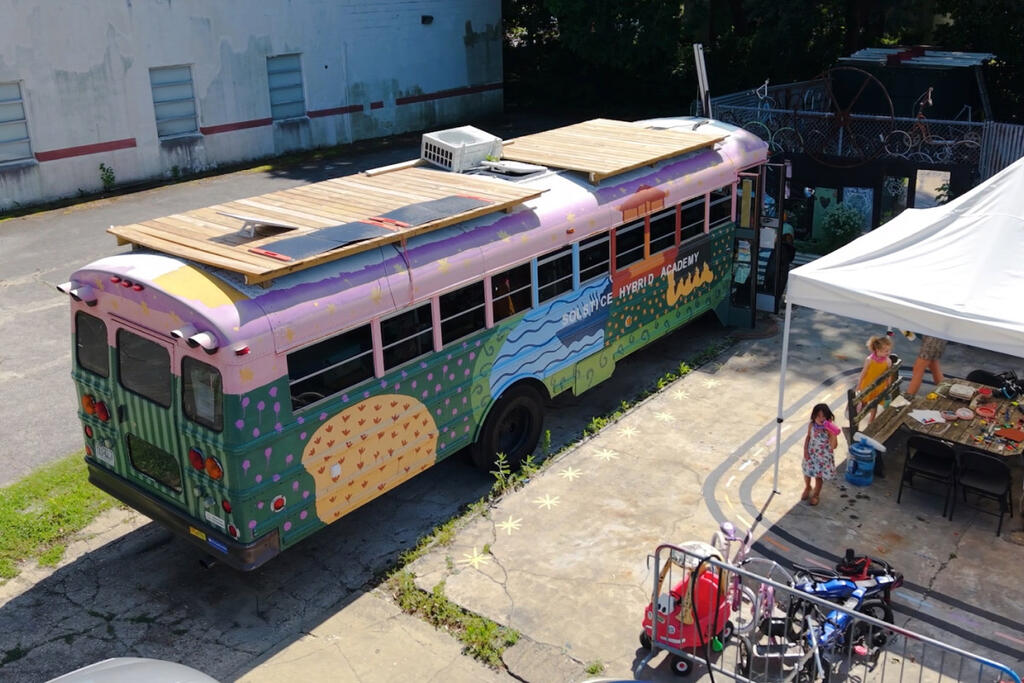 The converted school bus classroom, or “Skoolie,” features individual workspaces, storage, and ample floor space for hands-on activities.